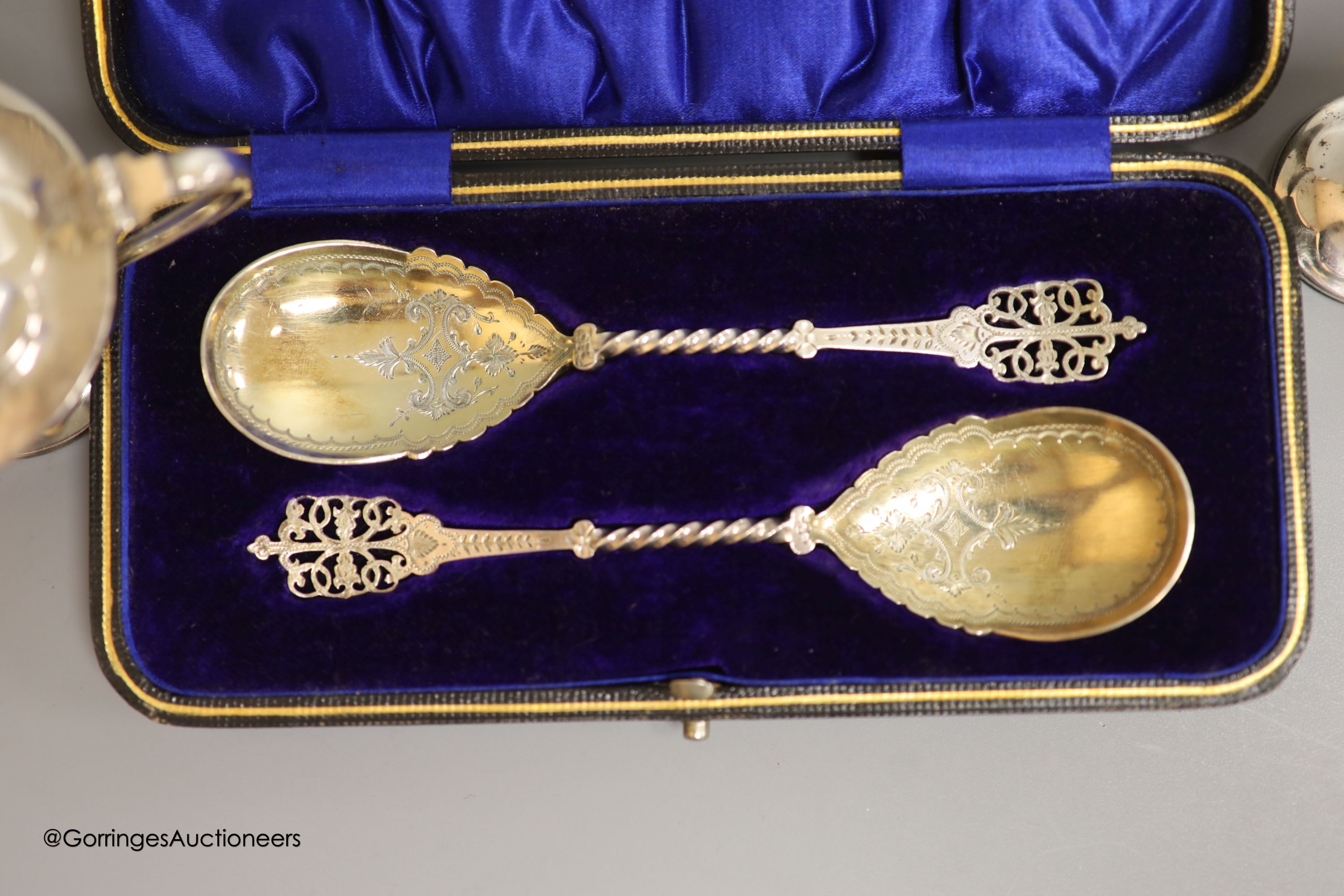 A cased pair of ornate Edwardian silver preserve spoons, Sheffield, 1905, a silver sauceboat, a silver hot water pot and two silver condiments